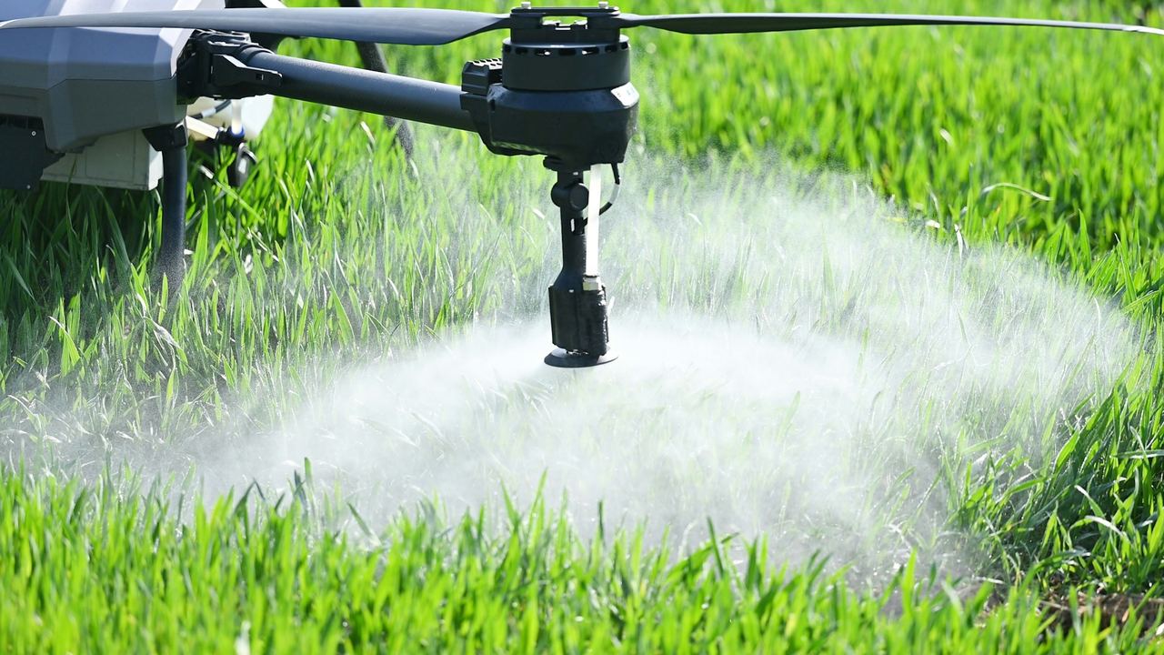 Spray mist from an agricultural drone over crops