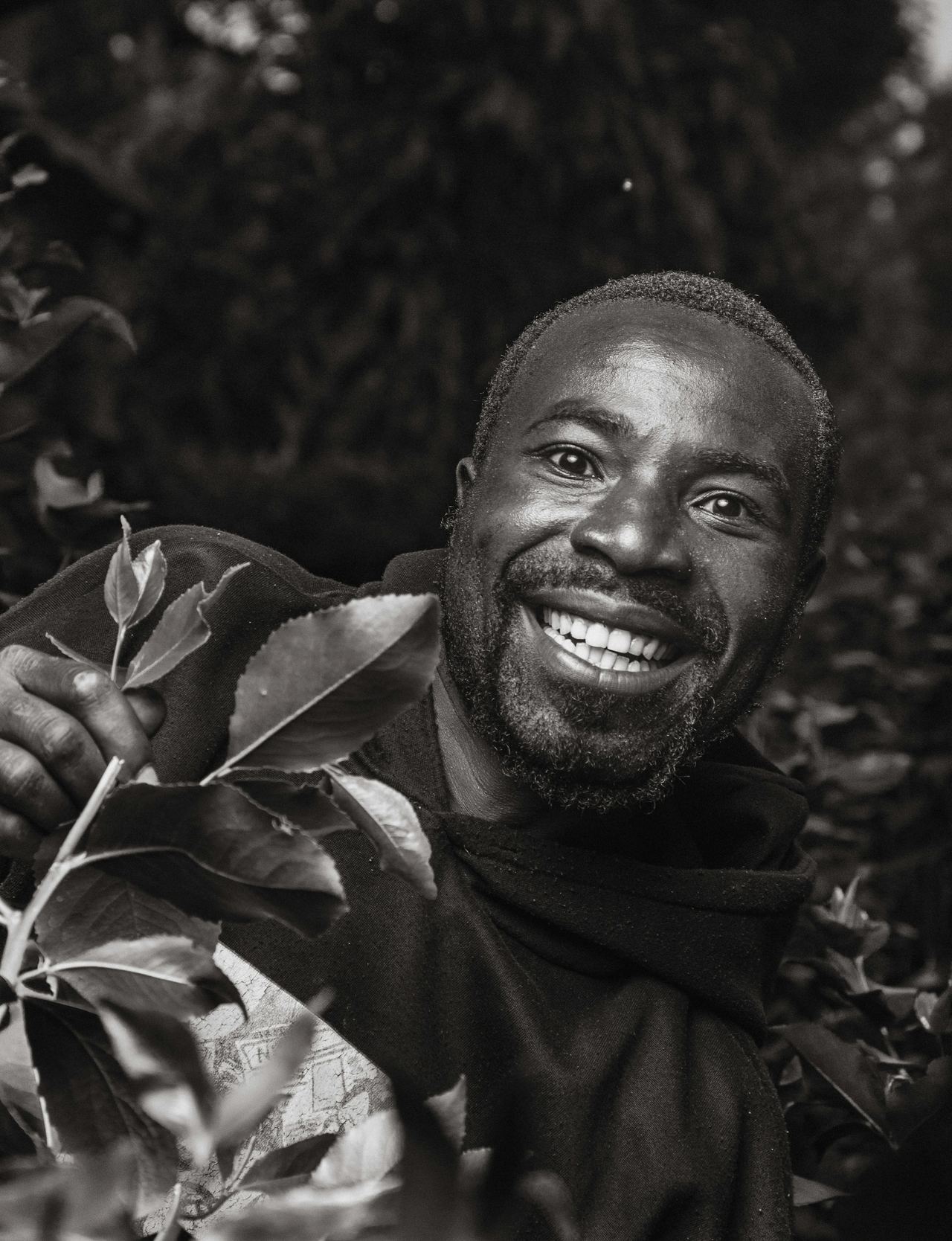 A smiling farmer holding a leafy branch